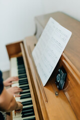Obraz premium childs hands playing on piano keys with sheet music and metronome