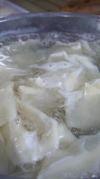 Close-up of fresh dough sheets boiling in hot water inside a metal pot for traditional beshbarmak