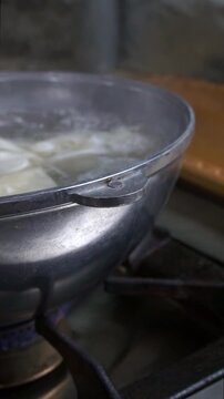 Close-up of fresh dough sheets boiling in hot water inside a metal pot for traditional beshbarmak