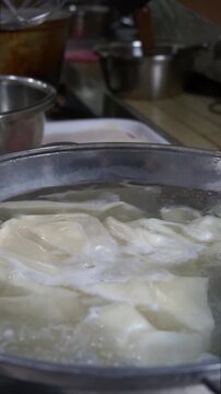 Close-up of fresh dough sheets boiling in hot water inside a metal pot for traditional beshbarmak