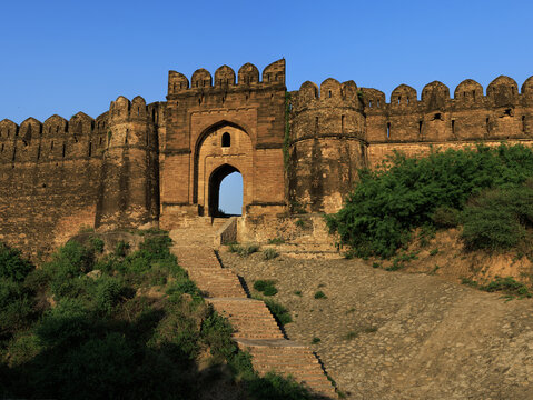 View of Rohtas Fort with its massive stone walls, arched gateway, and stone steps under a clear blue sky in Dina, Punjab, Pakistan.