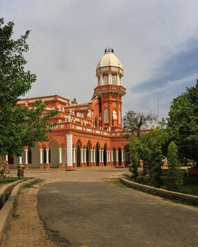 View of the historic Central Library Bahawalpur with its distinctive orange facade, white arched colonnades, and central tower surrounded by lush trees in Bahawalpur, Punjab, Pakistan.