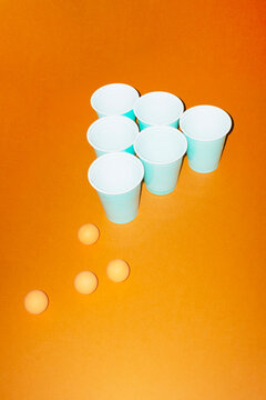 Ping pong ball and cup game on orange background