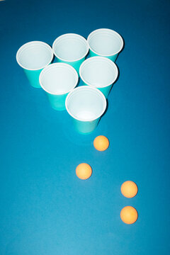 Ping pong ball and cup game on blue background