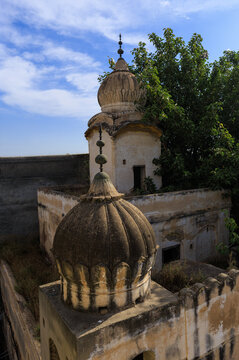 View of the historic Gurdwara saab Bhai Pheru featuring traditional domes and weathered stone architecture under a clear blue sky in Phool Nagar, Punjab, Pakistan.