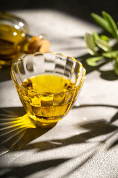 Golden olive oil in glass bowl with olive branch