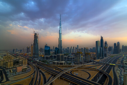 View of the Burj Khalifa towering over the modern Dubai skyline and complex highway interchange at sunset in Dubai, Dubai, United Arab Emirates.