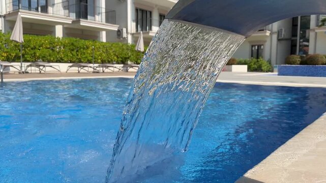 Water flowing into a hotel swimming pool on a sunny summer day, refreshing resort atmosphere and relaxing vacation concept