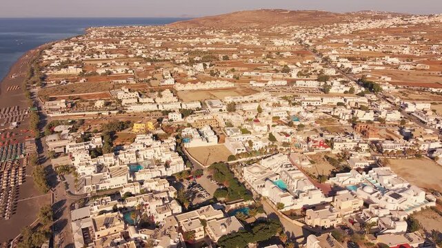 Drone shot of Perissa coastal town and black sand beach shoreline in Santorini Greece