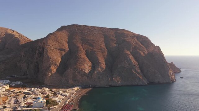 Drone shot of Mesa Vouno mountain cliff meeting Aegean Sea along Perissa shoreline Santorini Greece