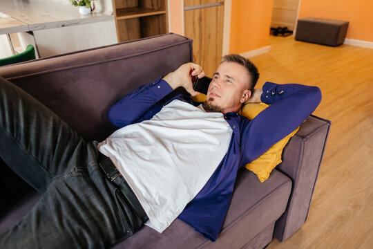 Man relax on sofa while talk on smartphone at home