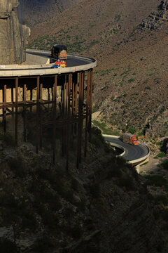 View of the winding mountain road at Fort Monroe, Iron Bridge, with colorful trucks navigating the steep cliffside pass in the rugged landscape of Fort Monroe, Punjab, Pakistan.