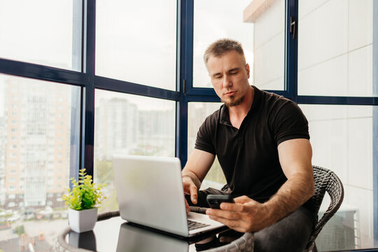 Man manage remote work on balcony with laptop and phone