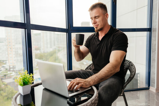 Man work remotely on balcony with laptop and coffee