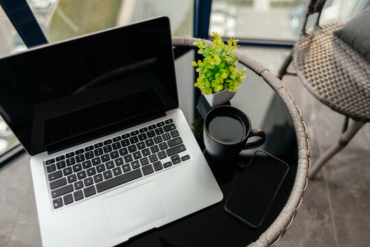 Remote work laptop setup on balcony table with coffee