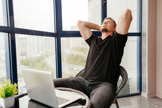 Relaxed man with laptop on balcony after remote work