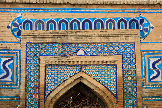 View of the historic 15th-century Tomb of Ghazi Khan featuring intricate blue and white glazed tile work and traditional brick masonry in Dera Ghazi Khan, Punjab, Pakistan.