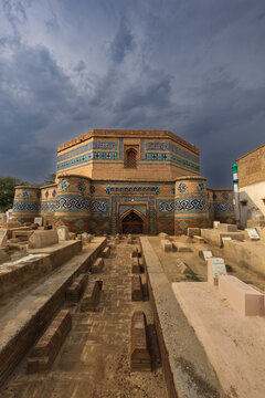View of the historic 15th-century Tomb of Ghazi Khan featuring intricate blue tile work and octagonal architecture, set within a traditional graveyard in Dera Ghazi Khan, Punjab, Pakistan.