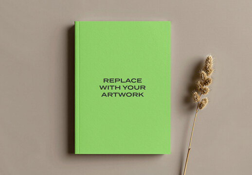 Hardcover book mockup with placeholder text displayed on a neutral surface, minimalist presentation featuring dried grass stem, cover design template for print