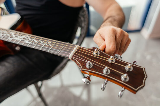 Man tune guitar on balcony before music performance