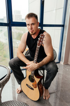 Man with acoustic guitar on apartment balcony