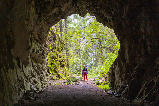 Hiker exiting a forest tunnel during a trekking adventure