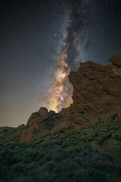 View of the Milky Way galaxy rising above the volcanic rock formations of Roques de Garcia in Paradores Canadas del Teide, Canarias, Spain.