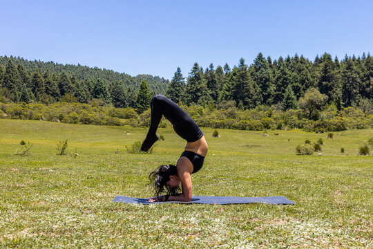 Woman practice yoga balance pose in sunny mountain meadow