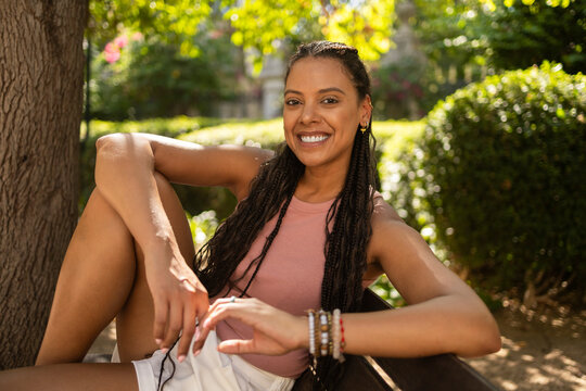 Smiling Hispanic woman with braids relaxing in park
