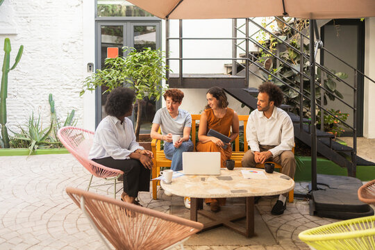 Coworking team discuss project at outdoor office patio