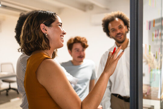 Coworking team review project plan on glass board