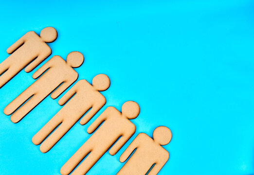 Five wooden human figures arranged diagonally as a team with copy space on turquoise background

