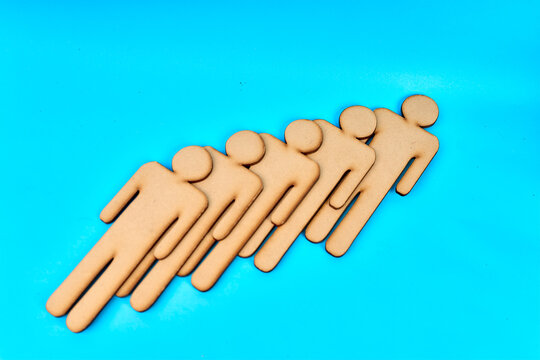 Five wooden human figures arranged diagonally symbolizing teamwork and unity on turquoise background
