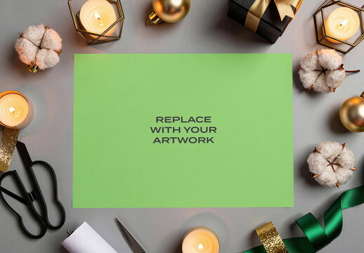 Paper mockup template for graphic design presentation, flat lay composition with holiday decor including candles, gift box, cotton stems, scissors, ribbons and ornaments on gray surface