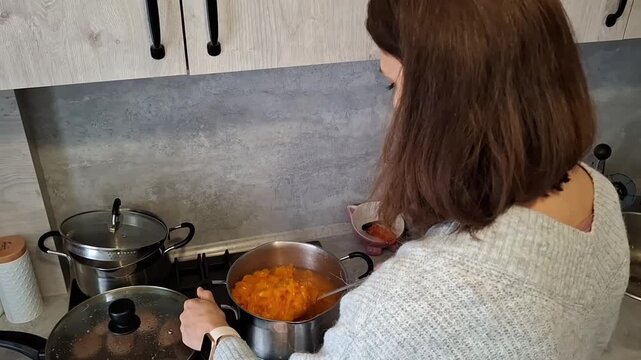Woman cooks in her kitchen while preparing a meal with vegetables and spices