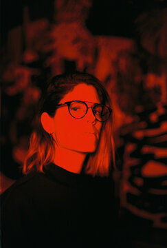 Woman in glasses under dramatic red light with shadow