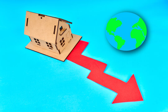Wooden house with red falling market arrow and globe on turquoise background
