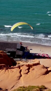 Parasailing Flying In Canoa Quebrada Ceara Brazil. Tourists Parasailing Over A Tropical Ocean On A Sunny Day. Bay Water Landscape. Landmark Beach. Canoa Quebrada Ceara.