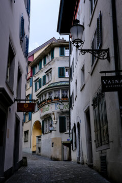 Zurich, Switzerland - March 15, 2026. Historic Veltliner Keller Building in a Narrow Cobblestone Alley of Zurich. A vertical, low-angle view captures a narrow cobblestone alley in the historic Altstad