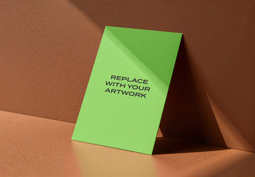 Vertical card mockup standing upright on a textured surface against warm brown wall, realistic stationery presentation with natural lighting, template for branding, print