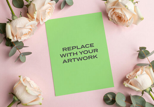 Vertical poster mockup on a pink background with white roses and eucalyptus, flat lay stationery presentation featuring artwork placeholder, graphic design template for branding, print