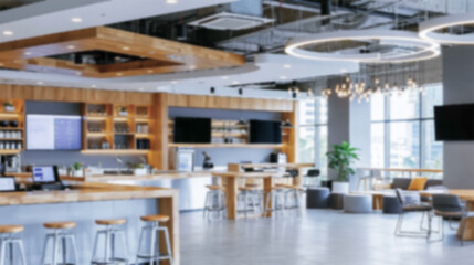 Fototapeta premium Blurred Background of a Modern Office Breakroom Featuring a Wooden Coffee Bar Counter with Stools and Comfortable Seating Areas in a Bright Open Concept Workspace Ideal for Professional Business