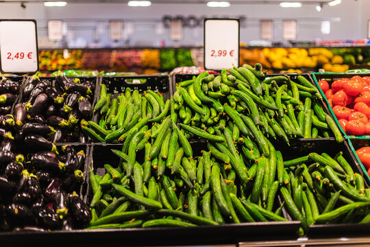 Fresh cucumbers eggplants and tomatoes displayed in supermarket produce aisle with healthy organic vegetables and grocery price signs