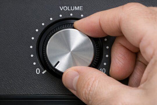 A close-up shot of a person's hand pressing the volume knob on an audio device