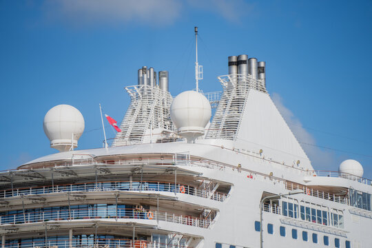 Passenger cruise ship upper deck featuring exhaust funnels satellite communication radomes and navigation mast representing maritime travel infrastructure