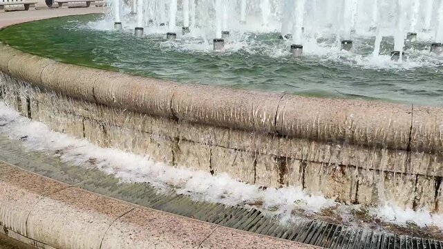 Tiered stone fountain with cascading water and multiple jets creating a dynamic urban landscape feature.