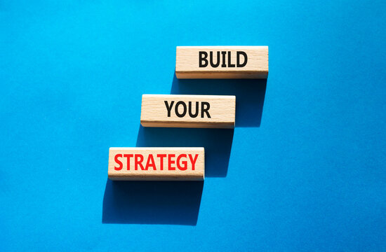 Build your strategy symbol. Concept words build your strategy on wooden blocks arranged as steps. Strategic planning concept. Blue background. Copy space.