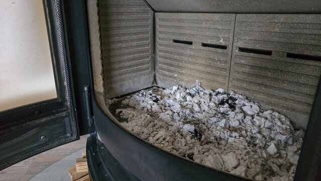Dirty wood stove chamber filled with cold ashes and charcoal ready for cleaning.