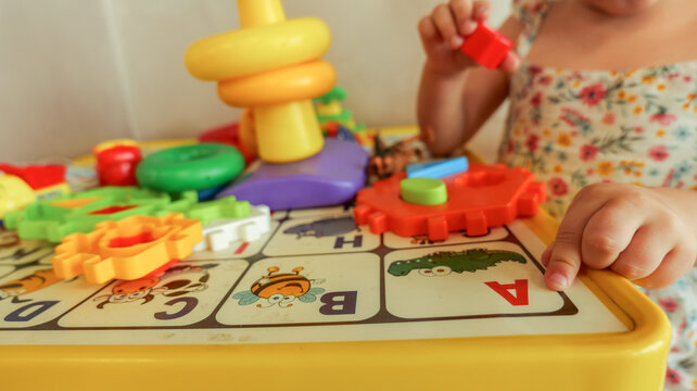 Toddler playing with colorful educational toys on a table with alphabet letters
