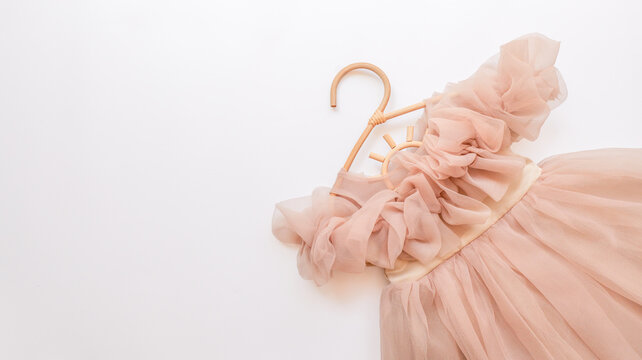 Delicate pink tulle dress with ruffles on a natural wood hanger